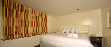Camera d'albergo con un letto grande, una testiera, un comodino e un telefono fissato al muro.