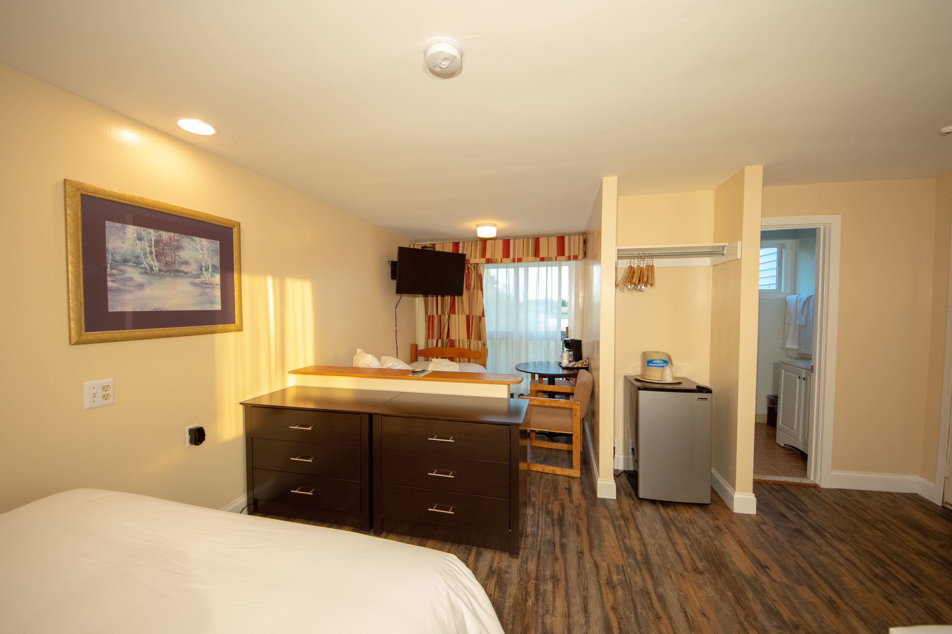 Una habitación de hotel con una cama, un escritorio con una silla, un televisor y un refrigerador pequeño.
