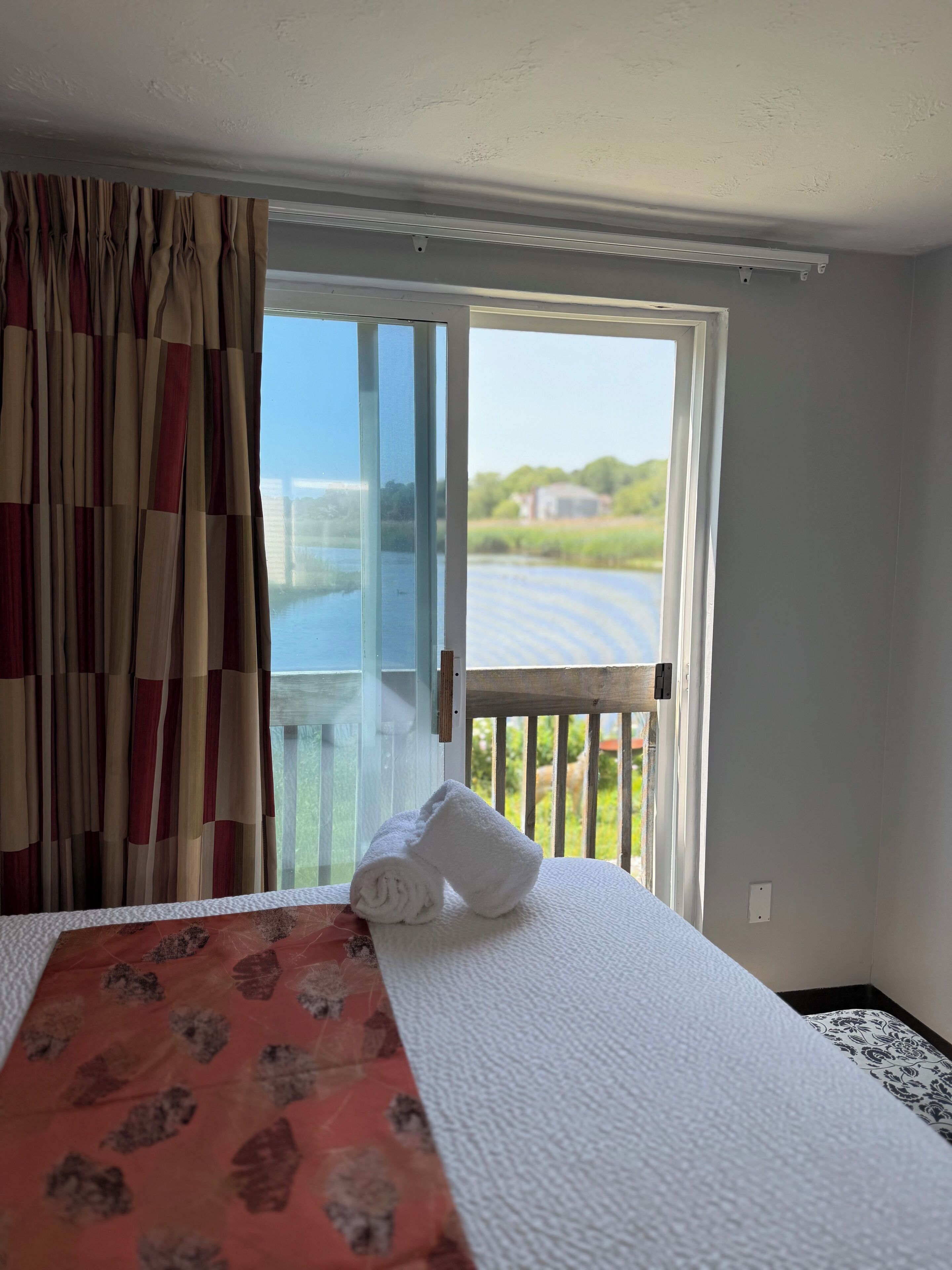 Una habitación de hotel con una cama, vistas a un lago y un balcón.