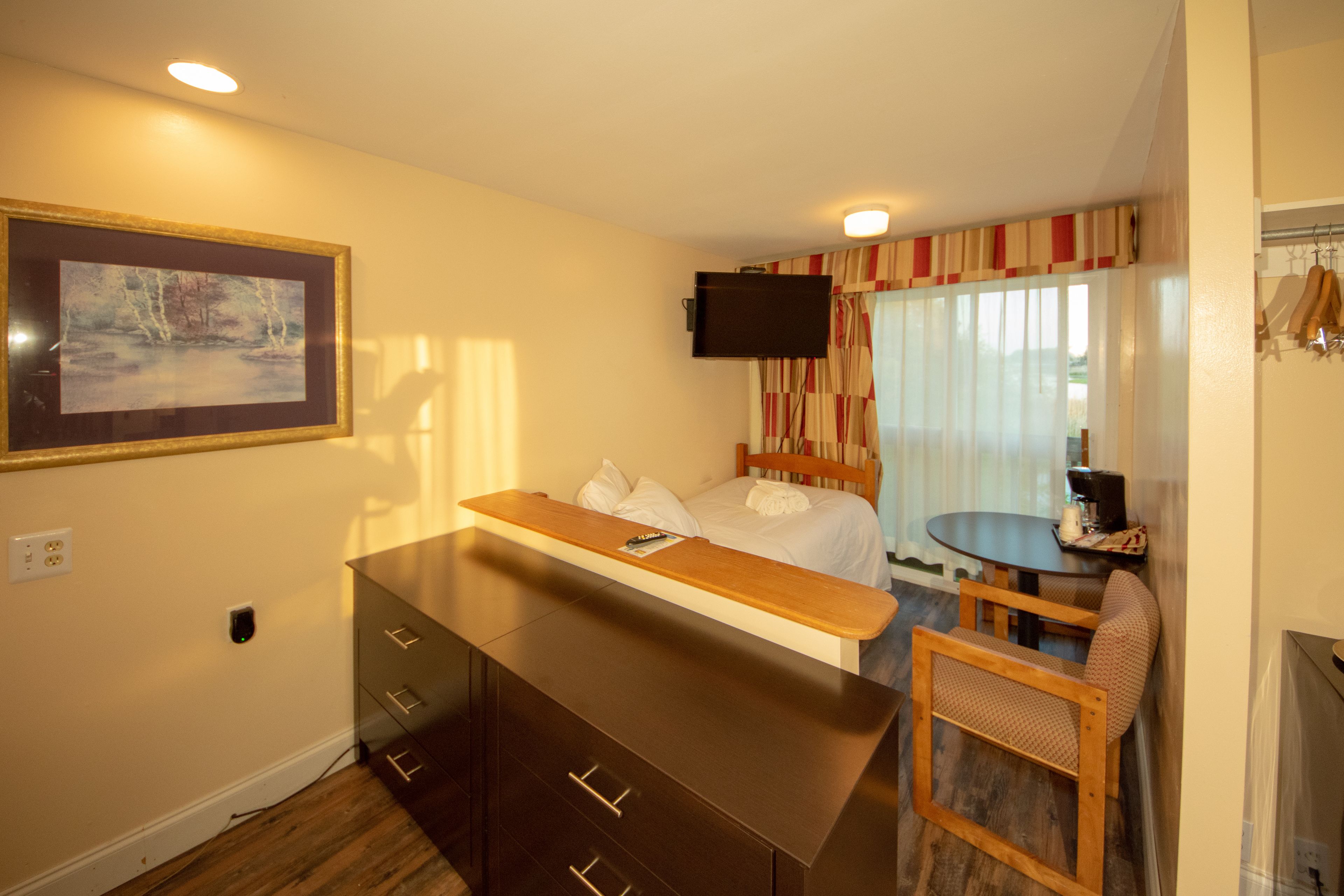 Une chambre d’hôtel avec un lit, un bureau, une chaise, une télévision et un tableau au mur.