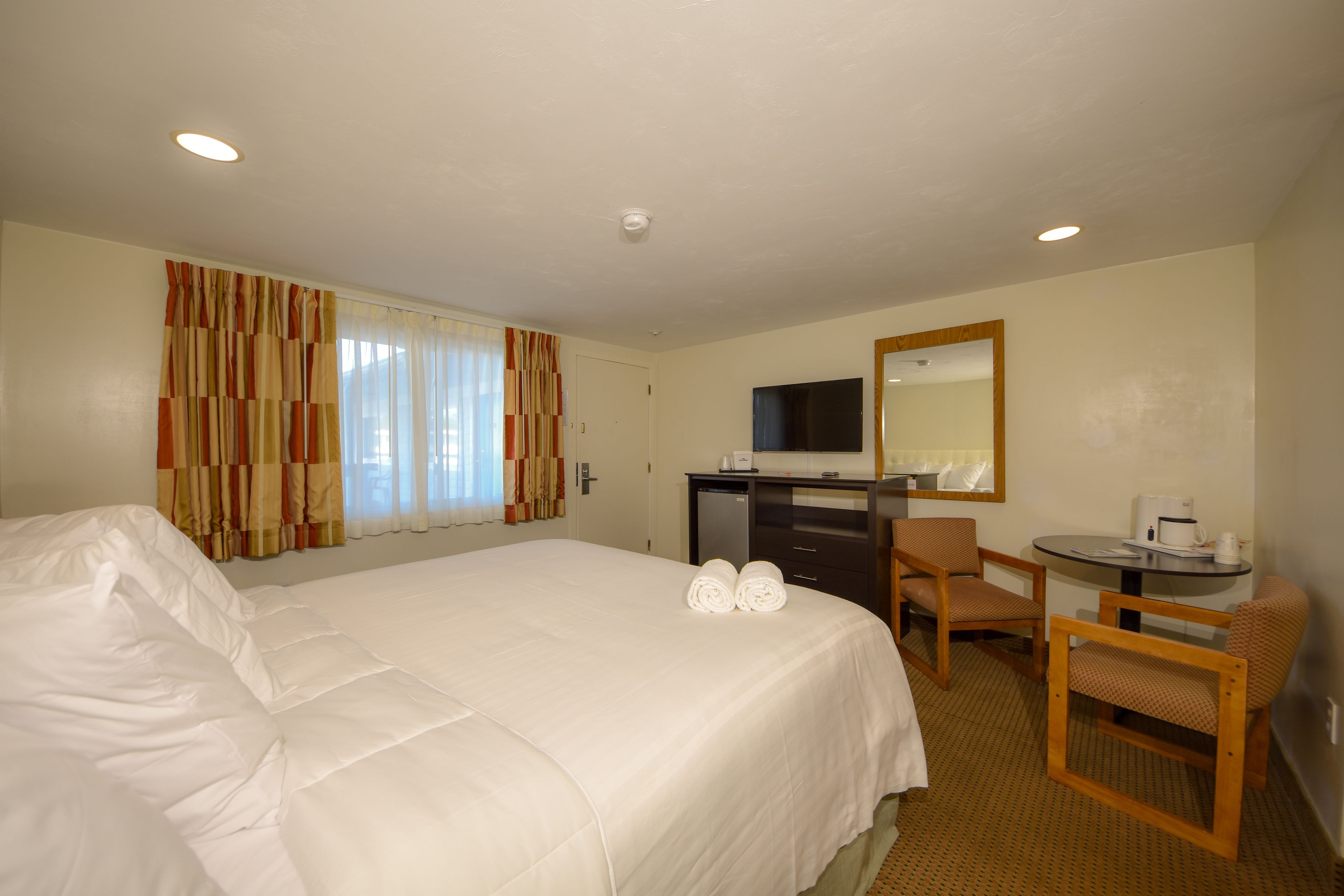 A hotel room with a large bed, a desk with a chair, a television, and a coffee maker.