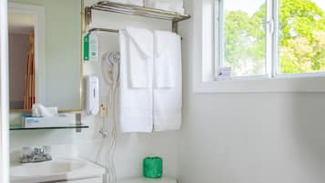 Un baño con inodoro, lavamanos y ventana con vistas a árboles.