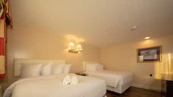 A hotel room with two beds, a nightstand, a desk, and a painting on the wall.
