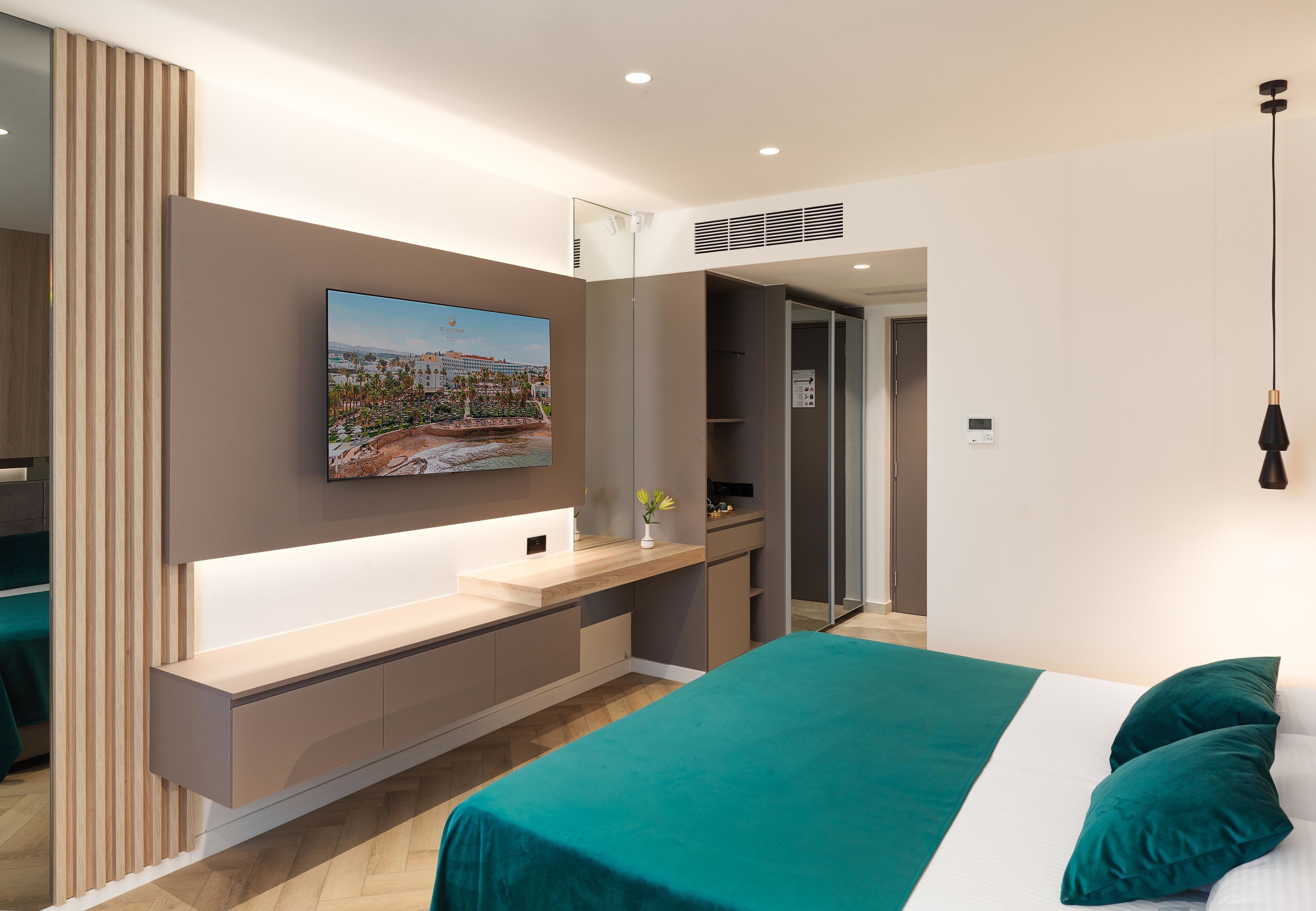 A modern bedroom with a bed, a bedside table, a mirror, and a wall-mounted TV.