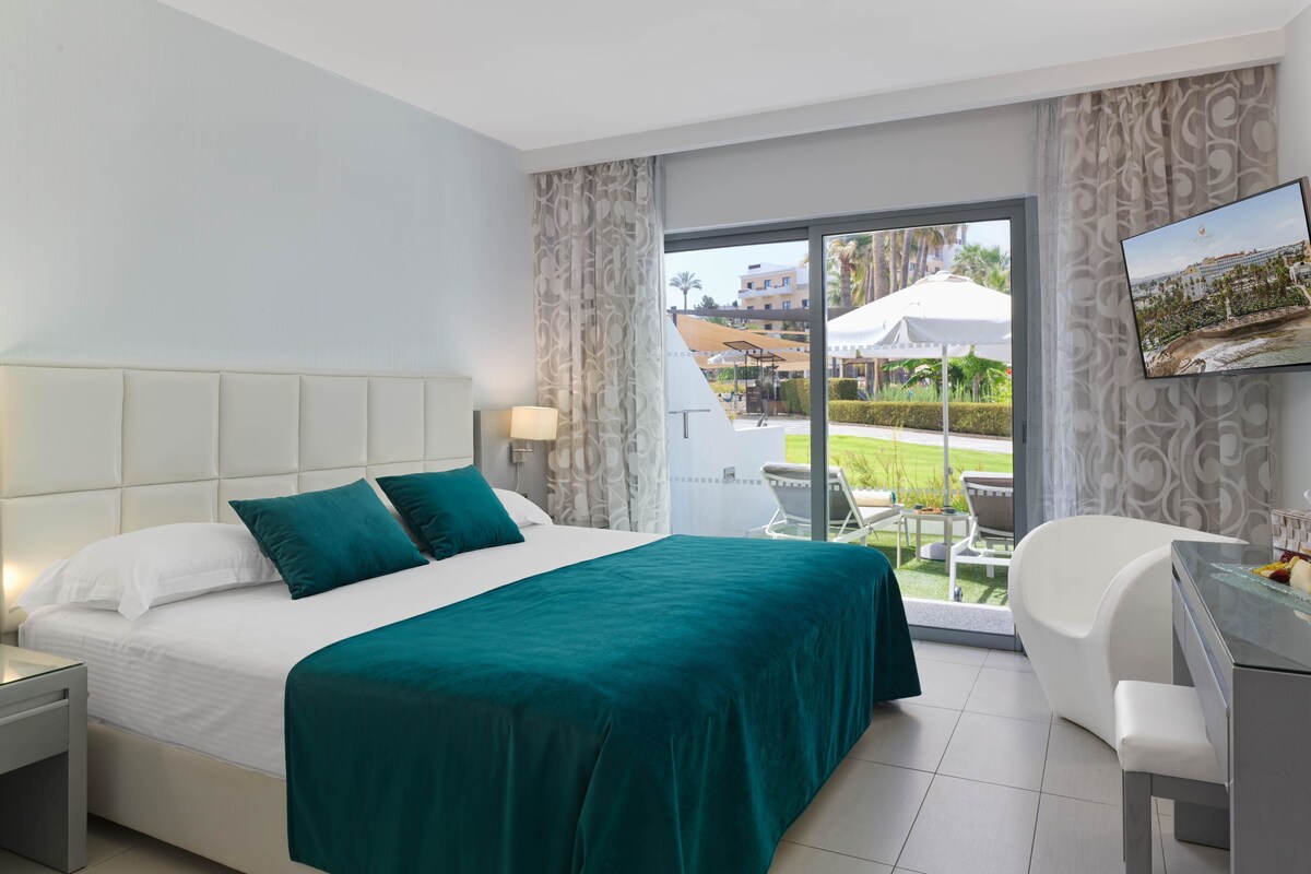 Una habitación de hotel con cama, escritorio, silla y vista al área exterior.