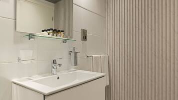 Un baño moderno con un lavamanos grande, espejo y repisa de vidrio con artículos de aseo.