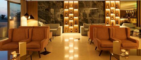 A modern lobby with two sofas, a marble wall, and a wine display.