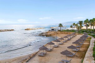 Na praia, espreguiçadeiras, guarda-sóis, toalhas de praia 