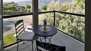 Un balcón con mesa y sillas, con vista a un paisaje pintoresco de árboles y montañas.