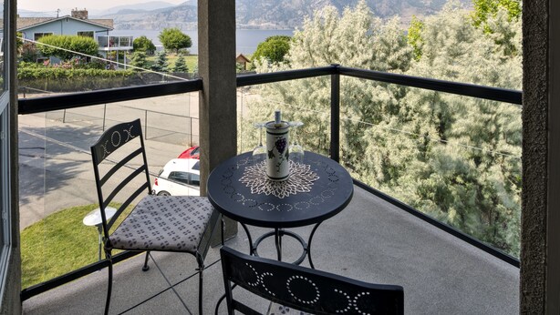 Varanda com mesa e cadeiras, com vista panorâmica de árvores e montanhas.
