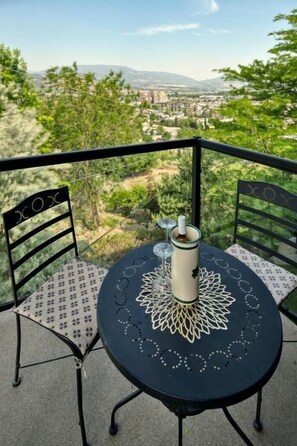 A balcony with a table and chairs, overlooking a cityscape. - Above The Beach Guest Suites (Penticton)