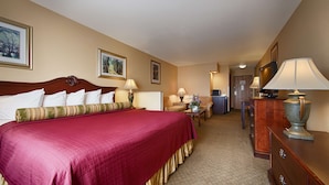 A hotel room with a large bed, two bedside tables with lamps, a dresser, and a desk with a lamp. - Best Western Penn-Ohio Inn & Suites (Hubbard)