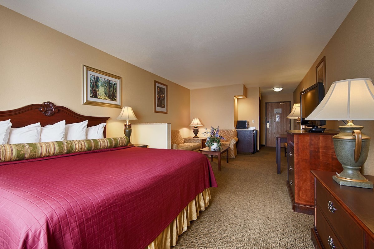 A hotel room with a large bed, two bedside tables with lamps, a dresser, and a desk with a lamp.