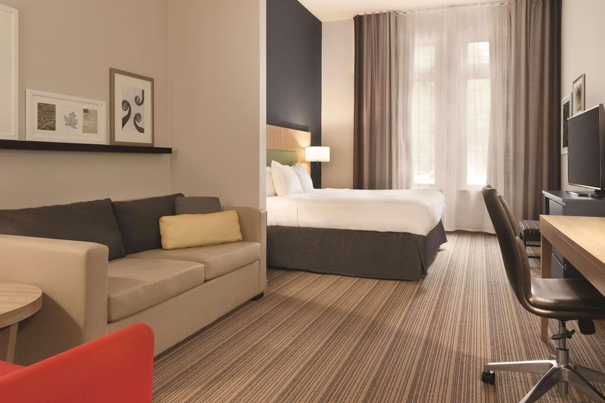 Una habitación de hotel con cama, sofá, escritorio y televisión.