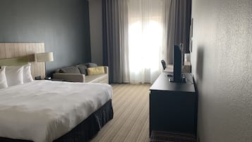 A hotel room with a large bed, a desk with a computer, a chair, and a TV.
