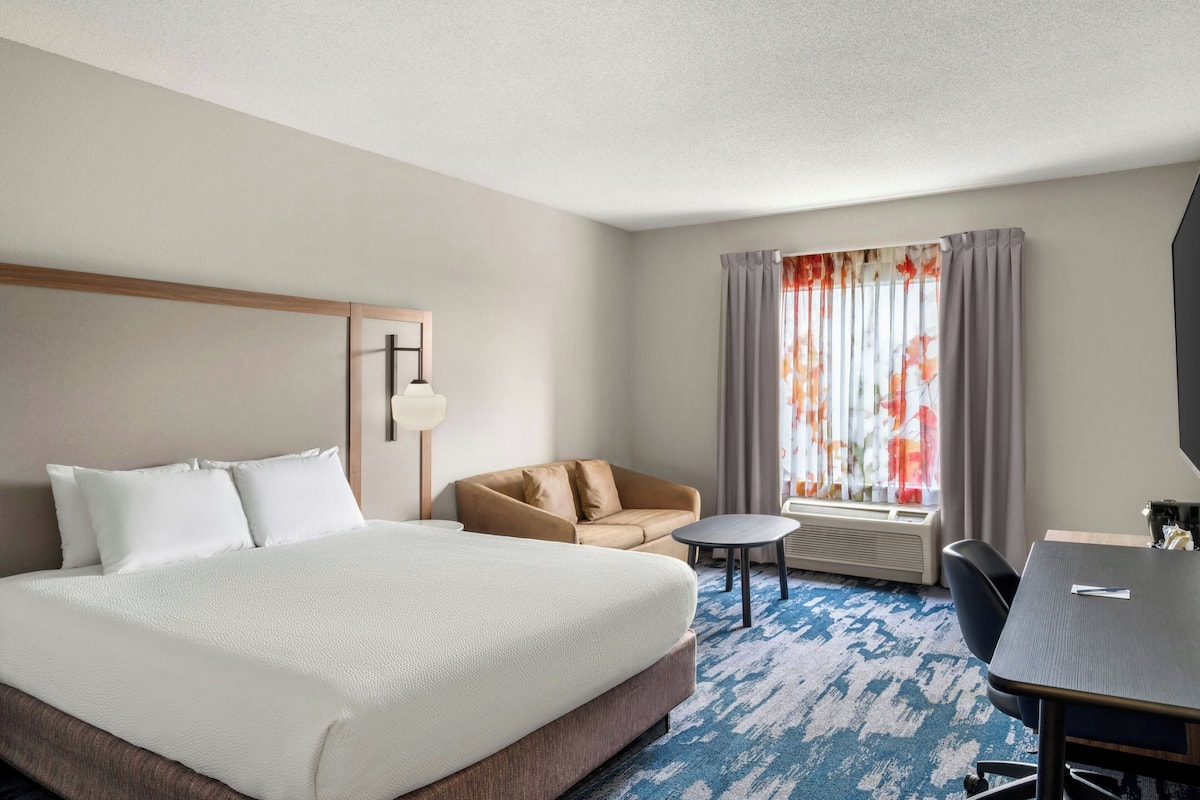 Een hotelkamer met een groot bed, een bank, een klein rond tafeltje en een bureau.