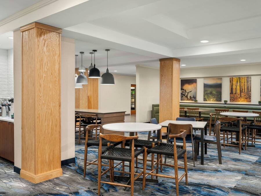 A modern dining area with wooden pillars, round tables, and black pendant lights.