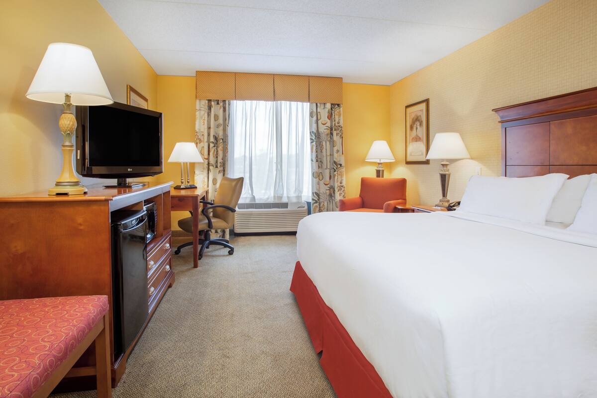 Ein Hotelzimmer mit Bett, Schreibtisch, Fernseher und einem Sessel.