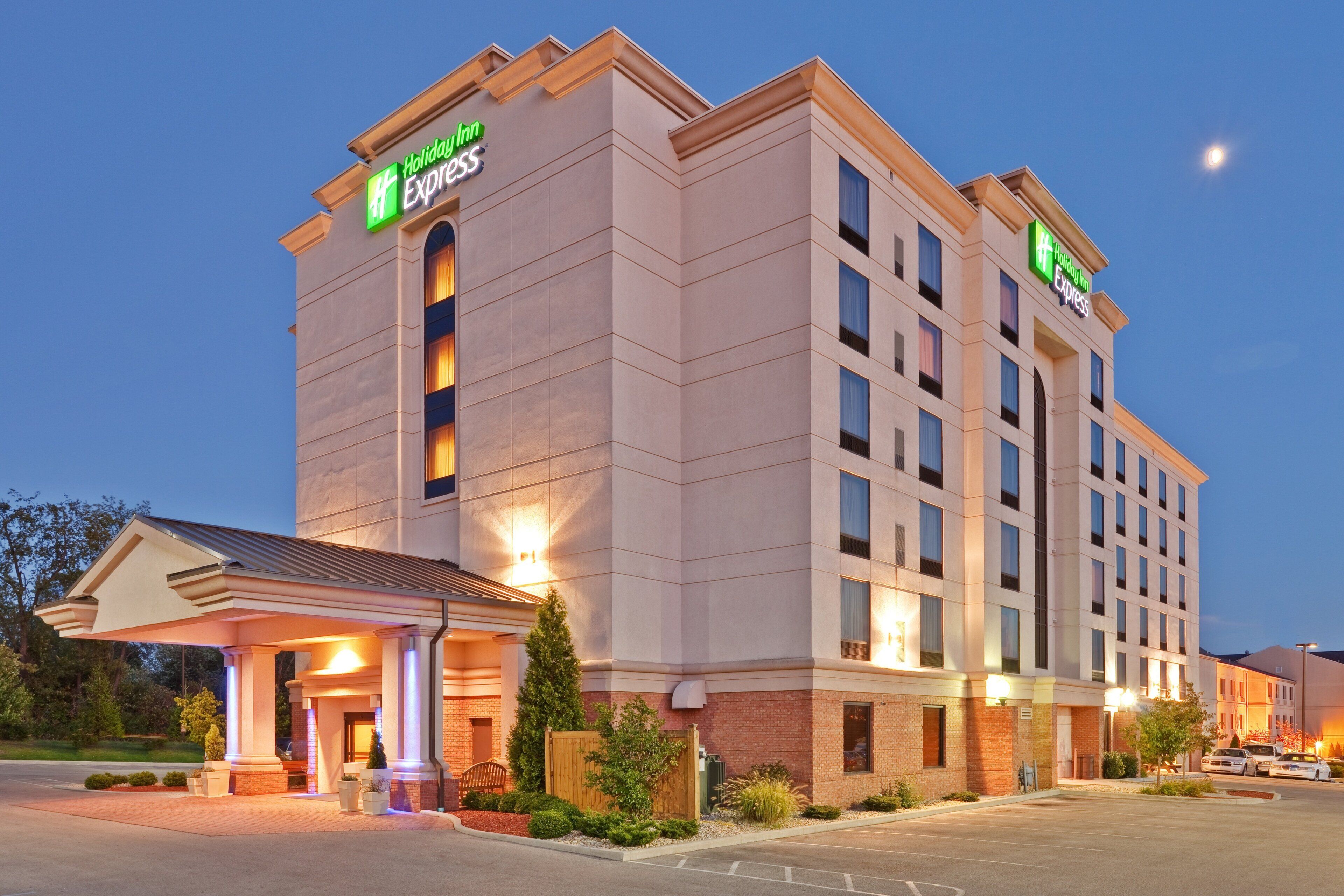 Um hotel Holiday Inn Express com design moderno, apresentando uma entrada destacada e um estacionamento.