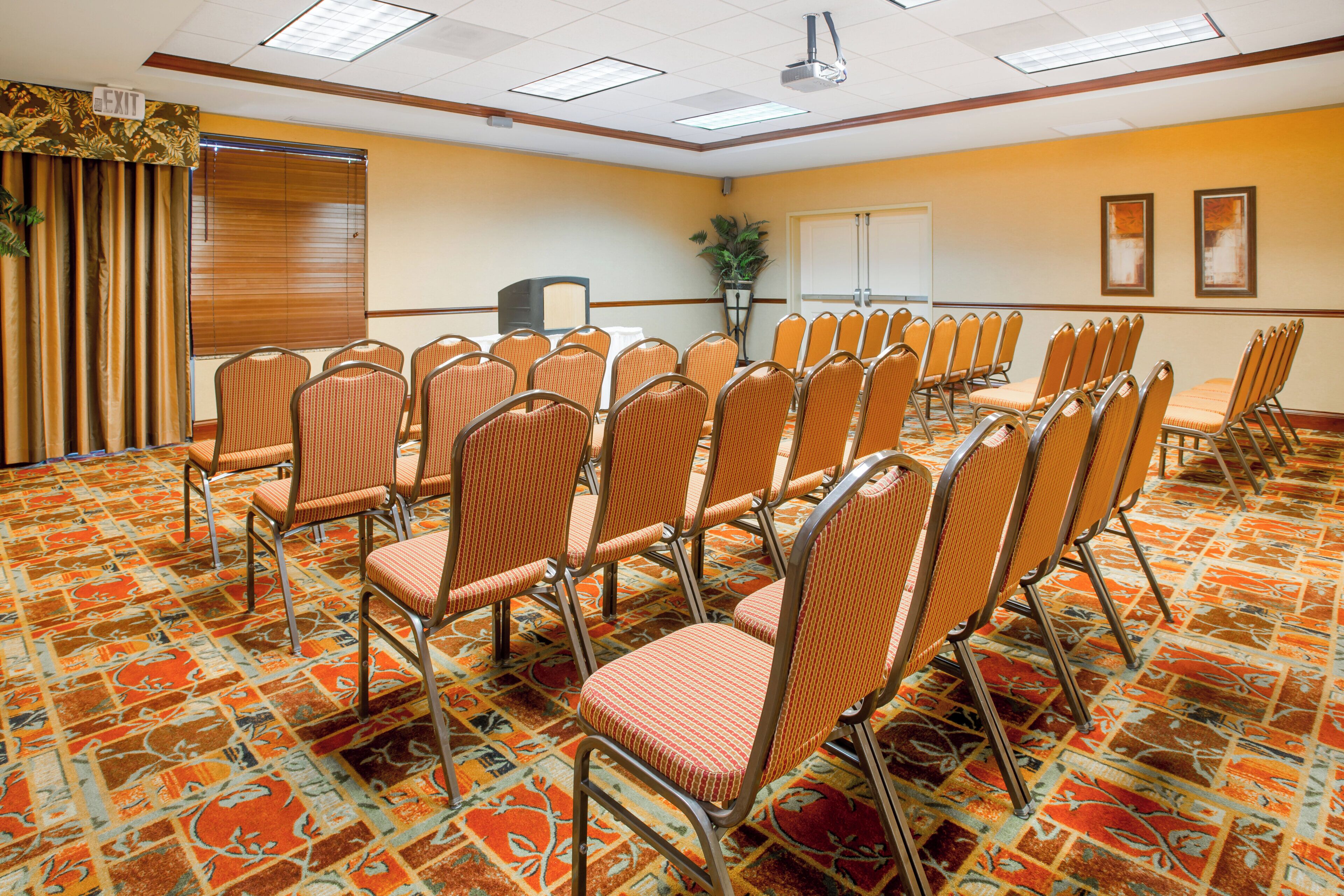 A conference room with rows of chairs, a projector, and a whiteboard.