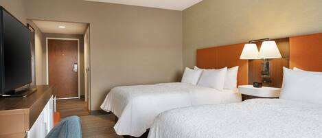 Une chambre d’hôtel avec deux lits, une télévision, un bureau et une lampe.