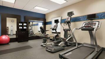A fitness center with treadmills, elliptical machines, and a red exercise ball.