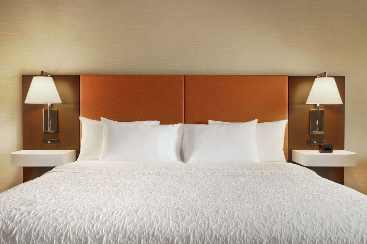 A hotel room with a large bed, two bedside tables with lamps, and a wooden headboard.