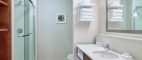 A modern bathroom with a glass shower enclosure, a white sink with a wooden vanity, and a large mirror.
