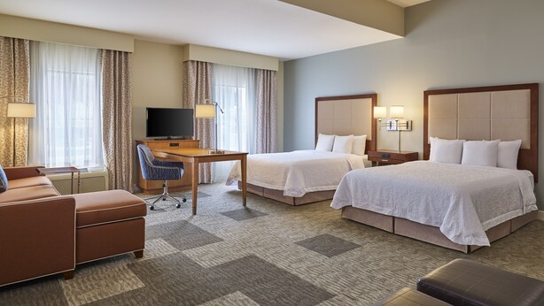 A hotel room with two beds, a desk, a TV, and a sofa. - Hampton Inn & Suites Schertz (Schertz)