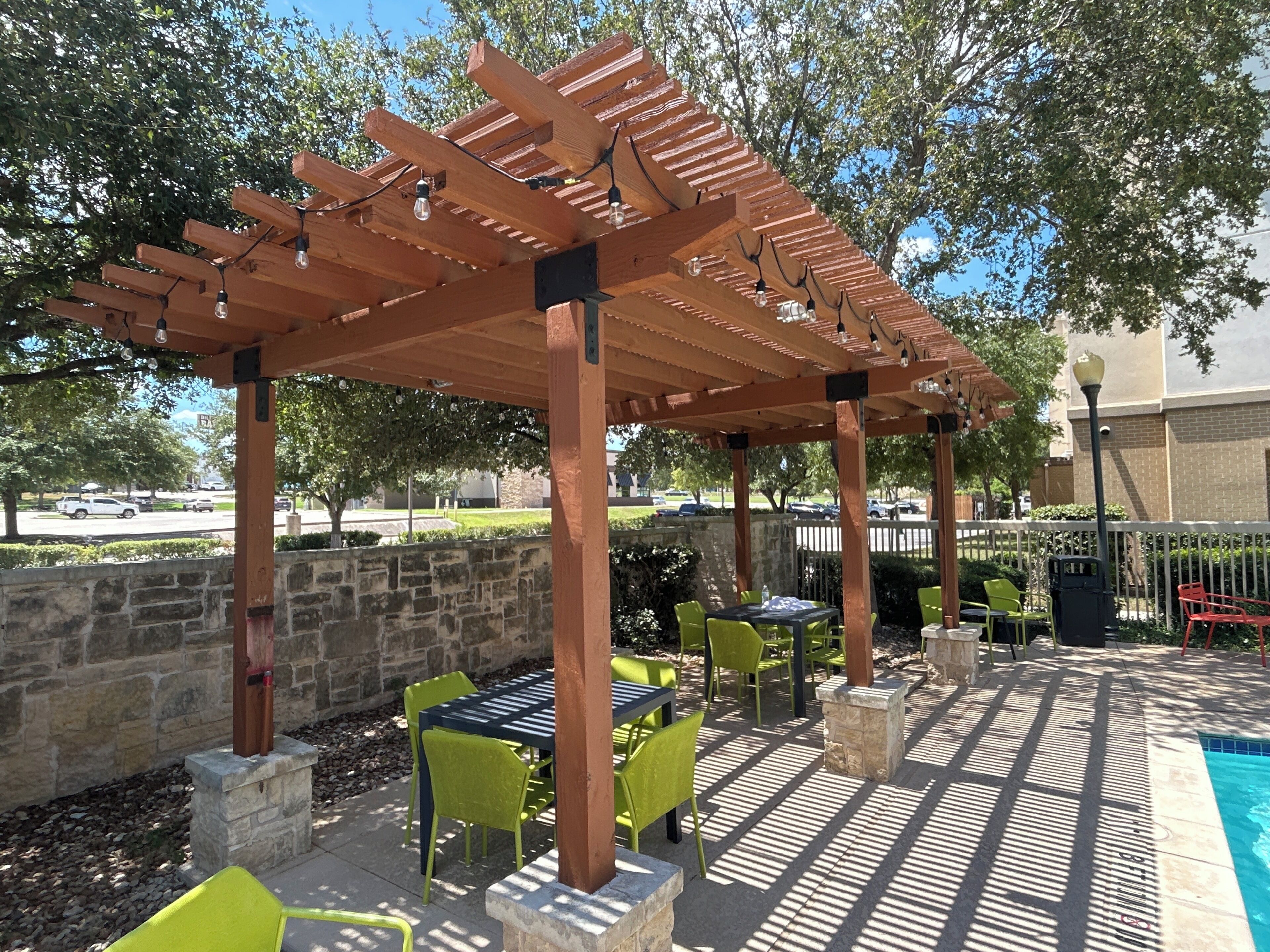 An outdoor patio with a pergola, stone walls, and outdoor seating.