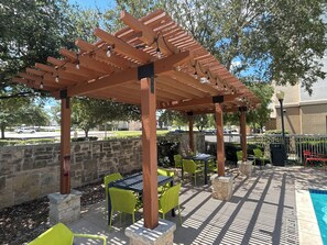 An outdoor patio with a pergola, stone walls, and outdoor seating. - Hampton Inn & Suites Schertz (Schertz)
