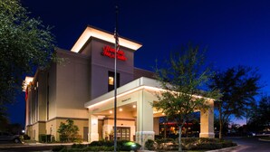 A hotel with a modern design, featuring a prominent entrance, a well-lit facade, and a flagpole. - Hampton Inn & Suites Schertz (Schertz)