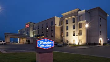 Een Hampton Inn & Suites hotel met een duidelijke ingang, parkeerplaats en een bord op de voorgrond.