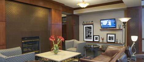 A hotel lobby with a fireplace, seating area, television, and decorative wall art.