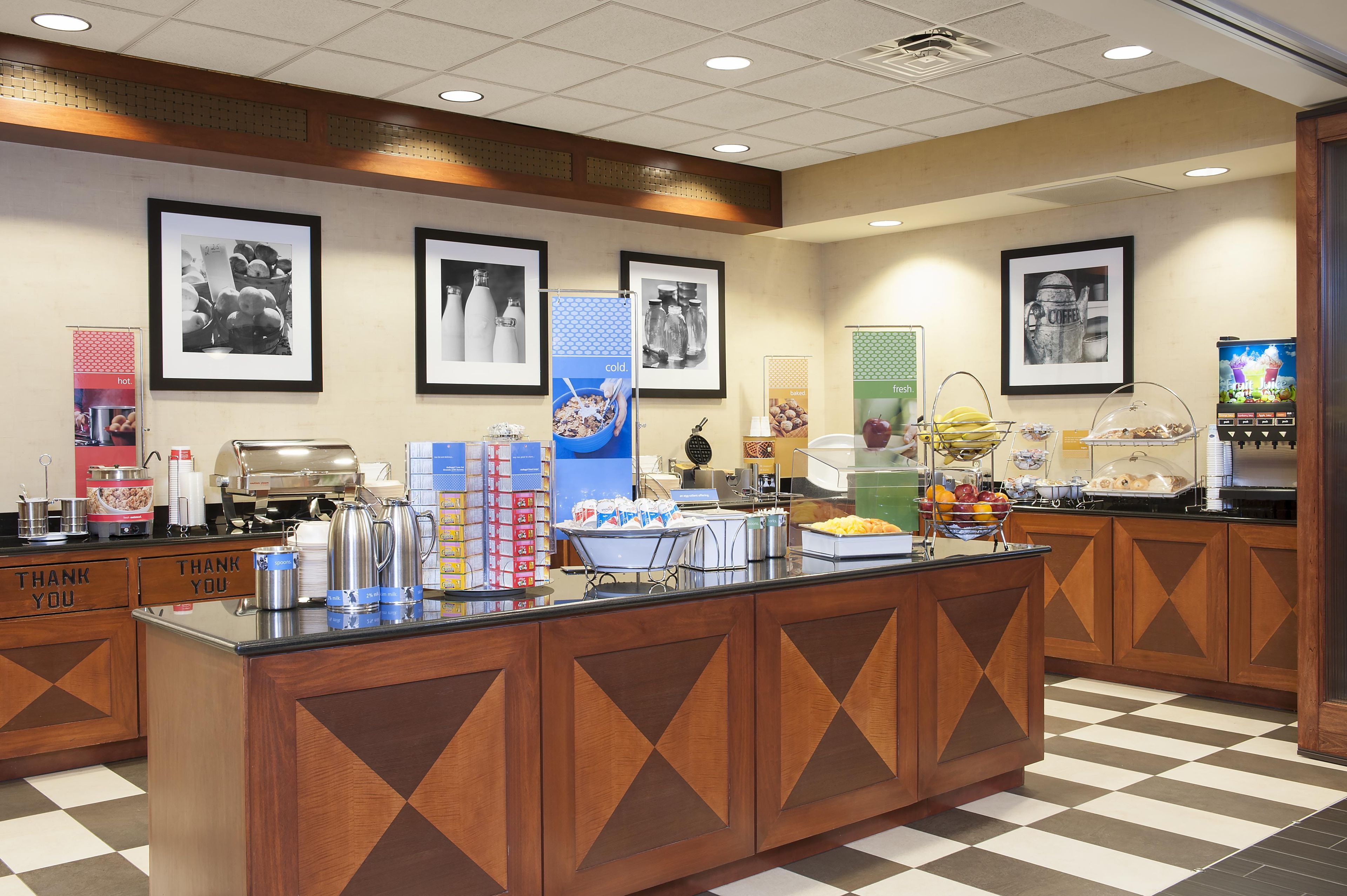 A breakfast buffet area with various food options, a coffee station, and a coffee machine.
