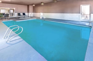 Una piscina con agua azul cristalina, un puesto de socorrista y sillas de descanso.