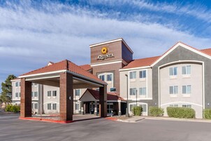 Hotel La Quinta con entrada cubierta, varios pisos y techo de tejas rojas.