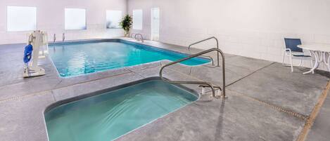 Piscina interna com prancha de mergulho e cadeira do salva-vidas.