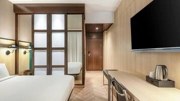 Une chambre d’hôtel comprenant un lit, un bureau, une chaise, une télévision et une armoire.