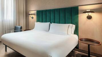 Una camera d'albergo con un letto grande, due comodini, una sedia e una finestra con tende.