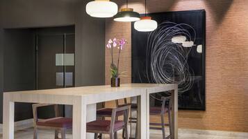 Un comedor moderno con mesa y sillas de madera, iluminación colgante y un cuadro abstracto grande en la pared.