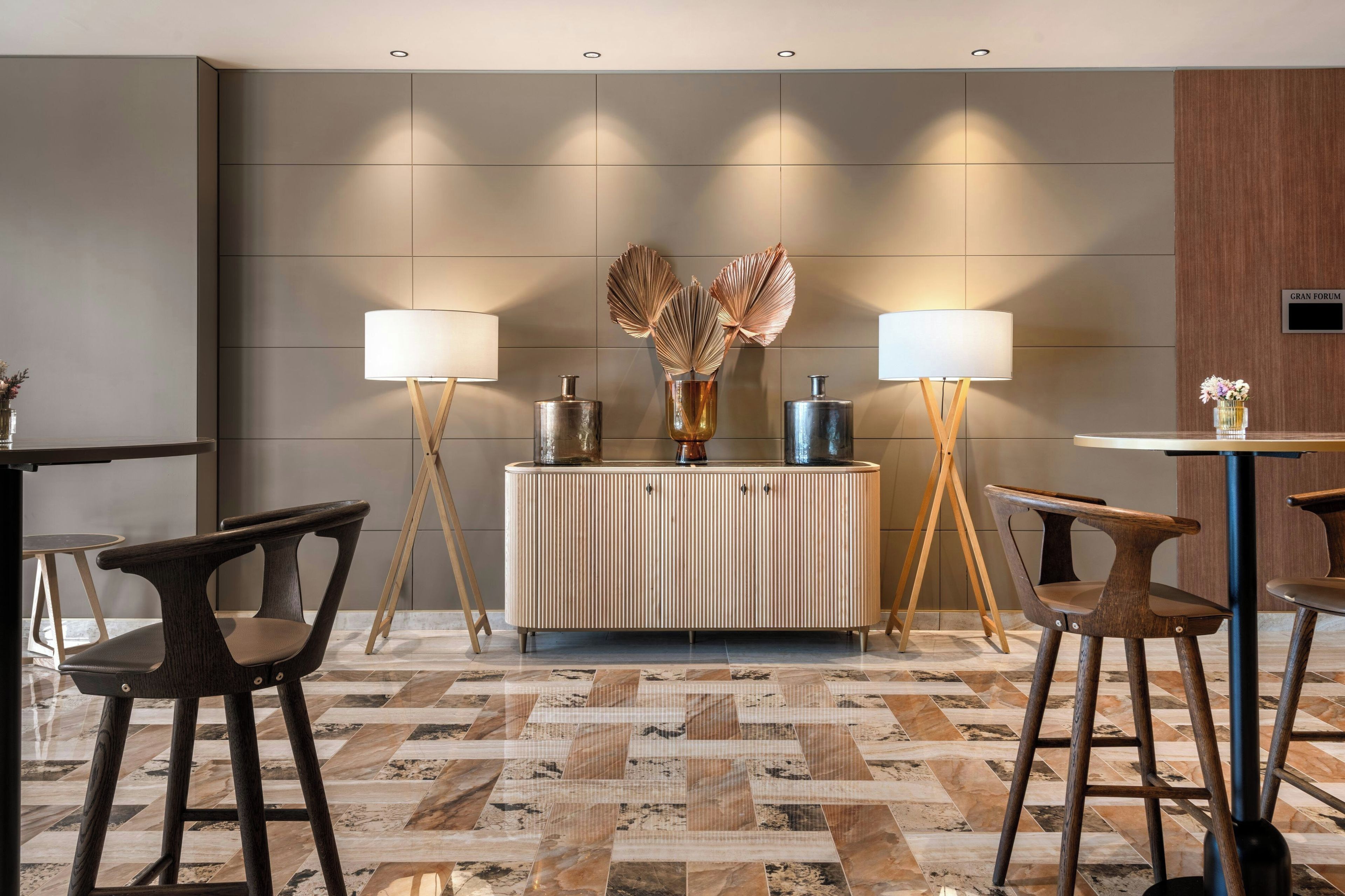 Un vestíbulo moderno con una recepción, dos lámparas de pie, un mueble decorativo y un suelo con diseño.