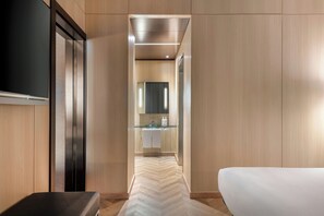 Una habitación de hotel con una cama, un televisor, un espejo y un baño con un lavabo de vidrio.