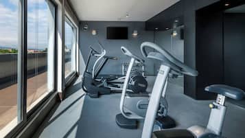Un gimnasio moderno con equipo de ejercicio, ventanas amplias y vista a la ciudad.