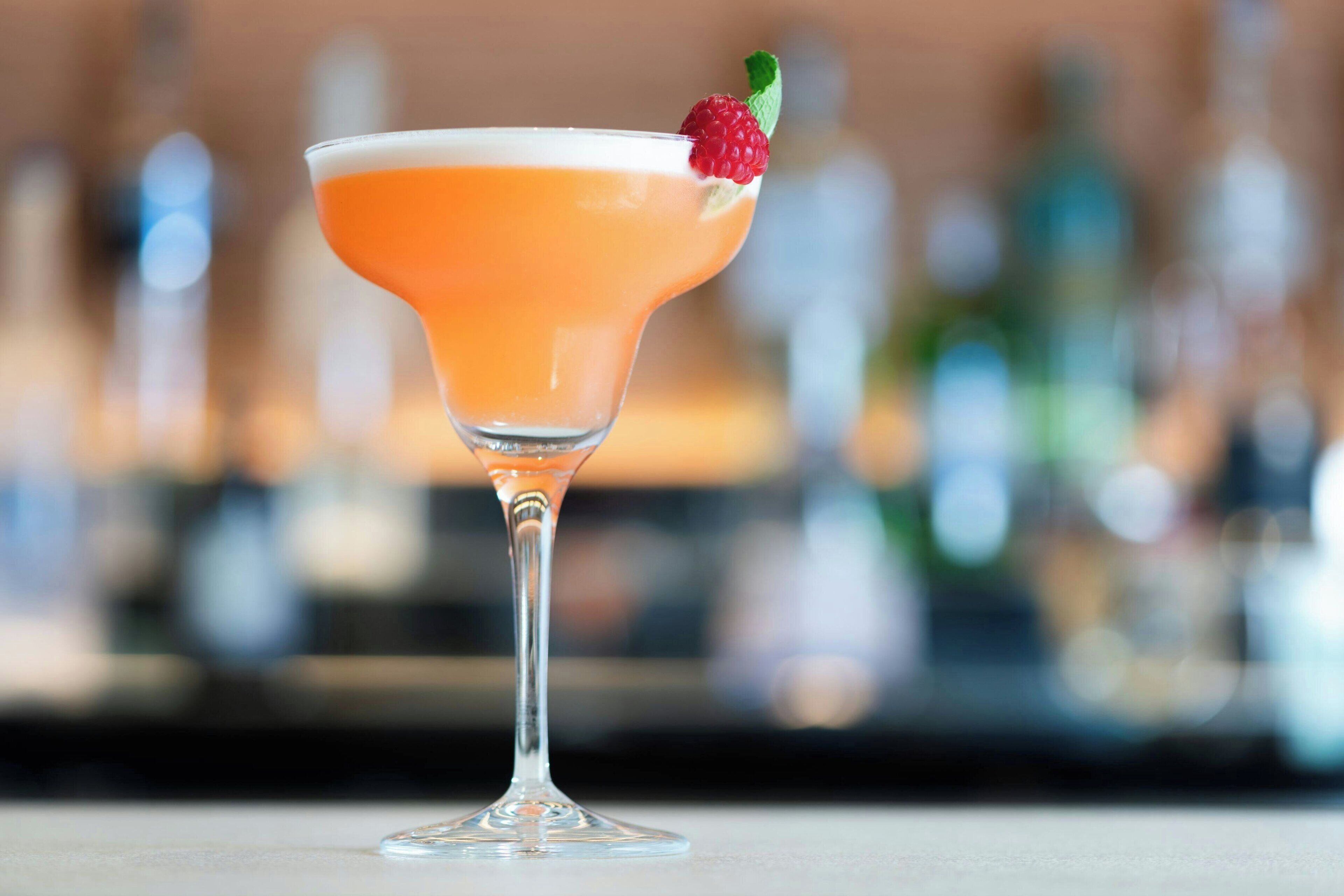 Un cóctel en una copa de martini, adornado con una fresa.