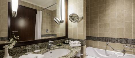 Un baño moderno con encimera de granito, dos lavamanos, un espejo grande y una bañera.
