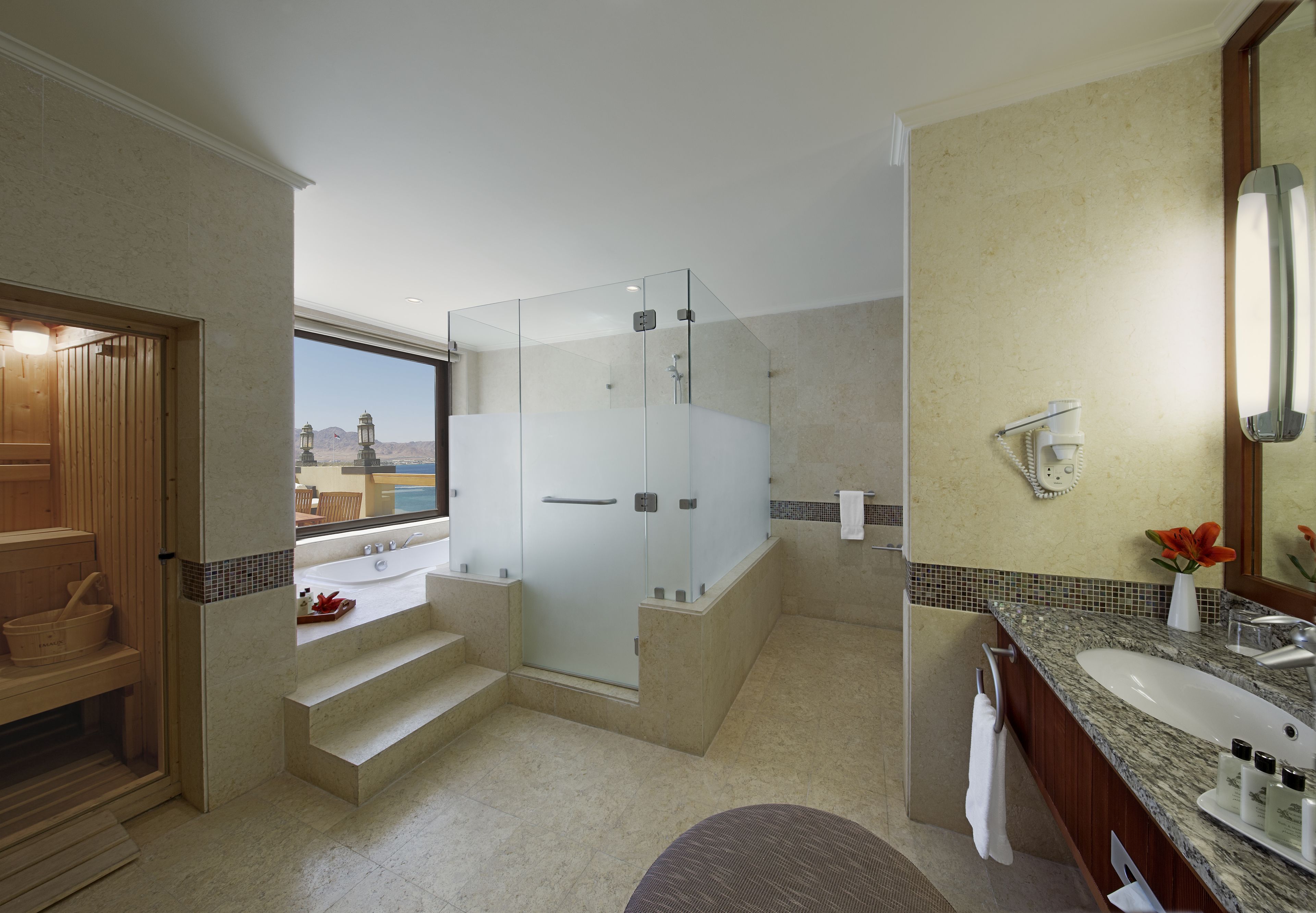 Un bany modern amb dutxa amb envàs de vidre, un gran lavabo i vista a un paisatge de muntanya.