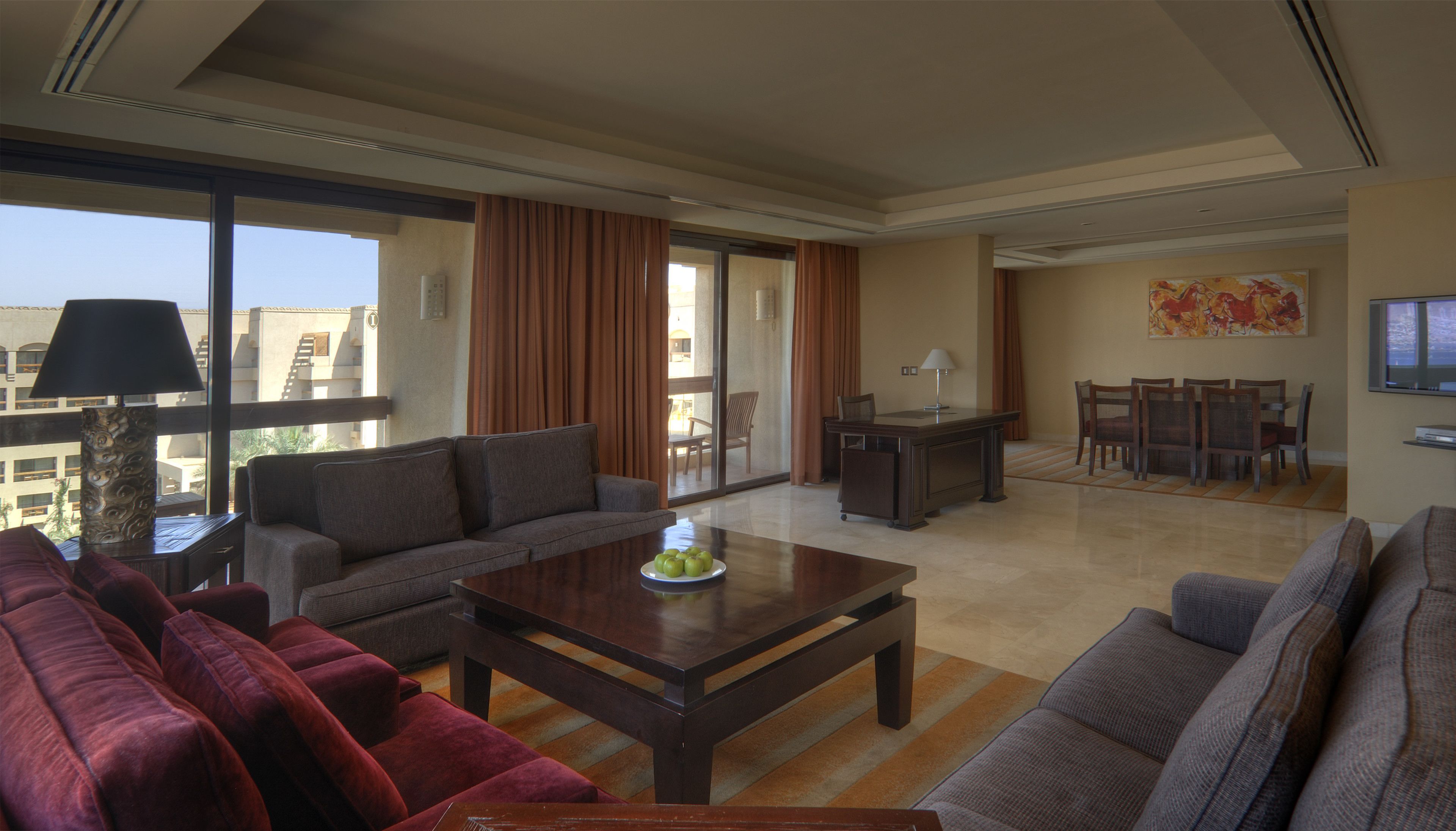 A spacious living room with a sofa, a coffee table, and a dining area with chairs and a table.