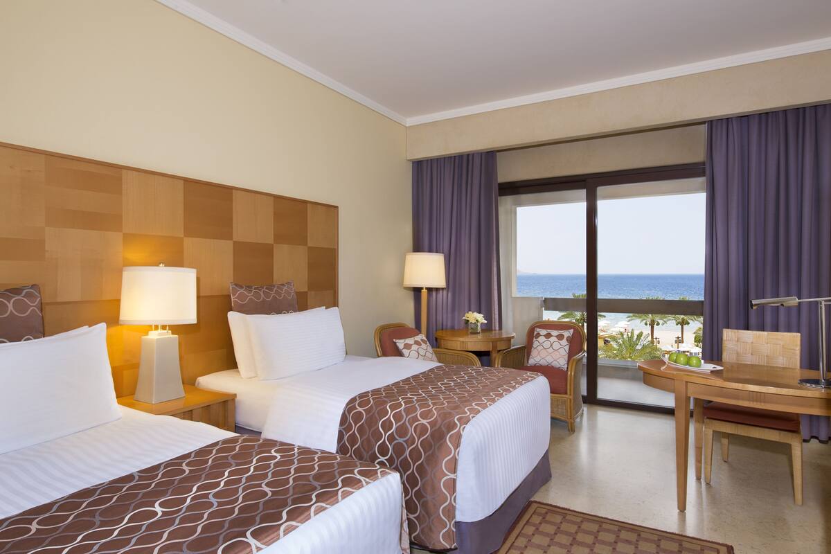 Ett hotellrum med två sängar, en matplats och utsikt över stranden.