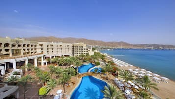 Relax by the pool or on the beach, surrounded by palm trees and a scenic view.